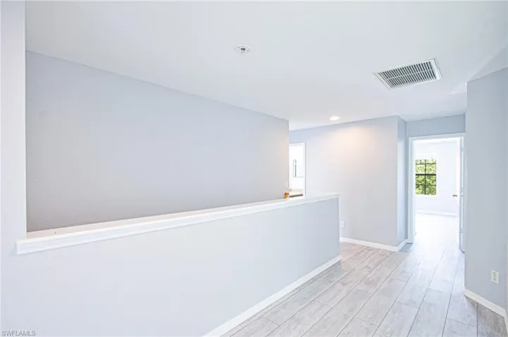 Corridor with light wood finished floors and recessed lighting