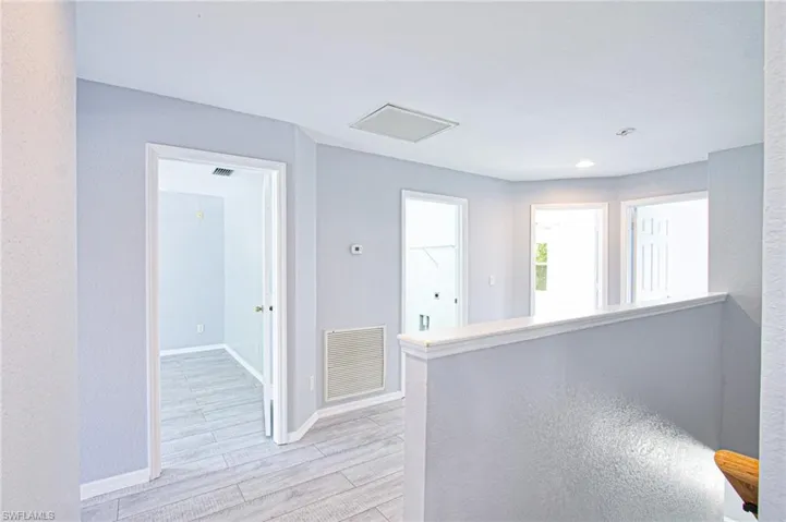 Kitchen with light wood-style floors, light countertops, and a textured wall
