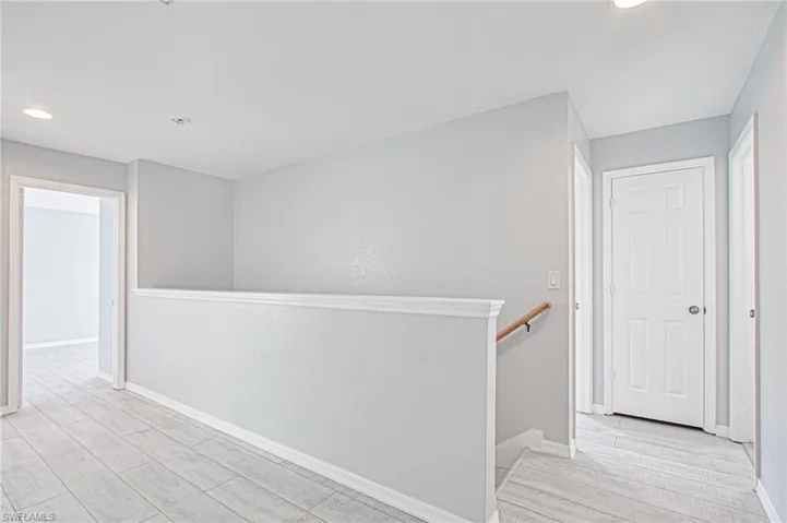 Corridor featuring recessed lighting, wood finish floors, and an upstairs landing