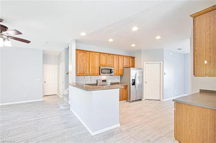 Kitchen featuring appliances with stainless steel finishes, brown cabinets, a peninsula, recessed lighting, and light wood-type flooring