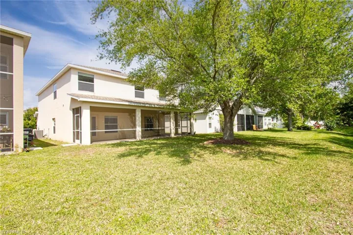 Rear view of house with a lawn, a sunroom, and stucco siding