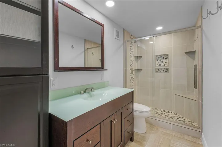 Bathroom featuring vanity, a shower with shower door, and toilet