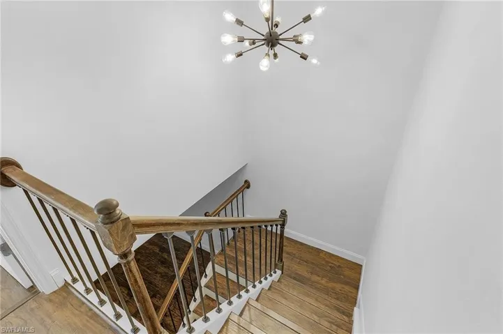 Staircase featuring wood-type flooring and an inviting chandelier
