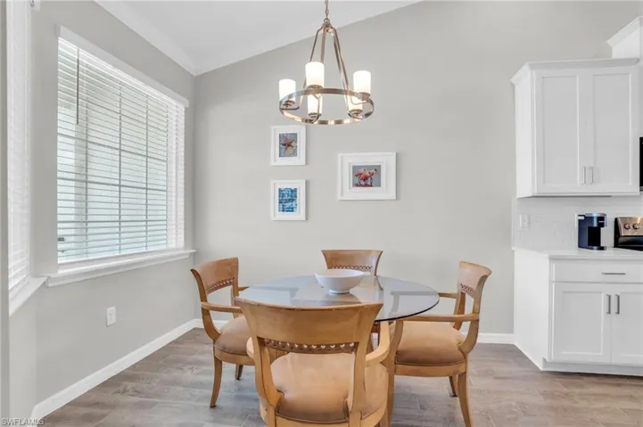 Dining space featuring light wood-style floors, baseboards, a notable chandelier, and ornamental molding