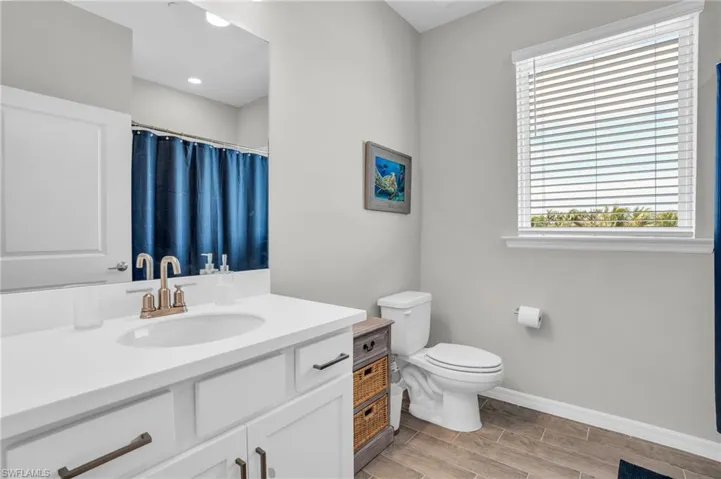 Bathroom featuring curtained shower, baseboards, toilet, and vanity