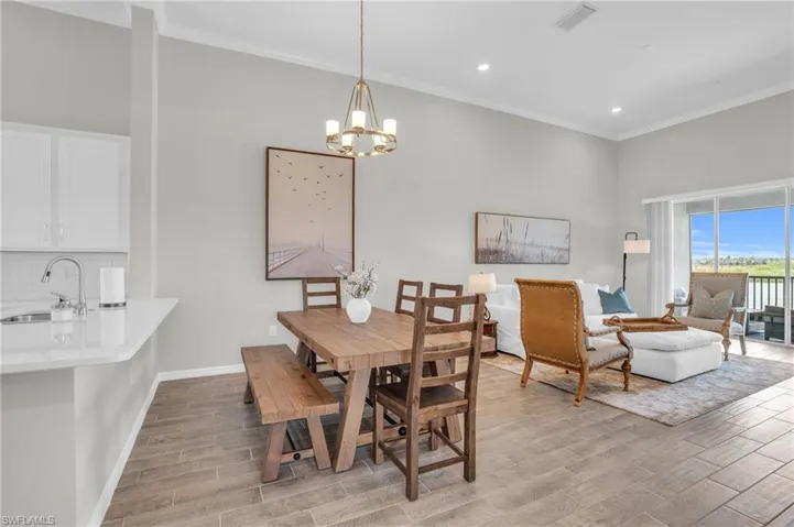 Dining space with wood tiled floor, ornamental molding, visible vents, and a chandelier