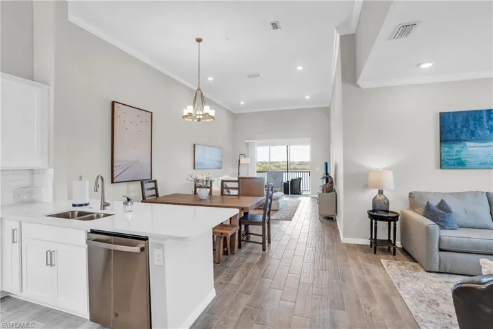 Kitchen featuring visible vents, a sink, open floor plan, dishwasher, and light wood-type flooring