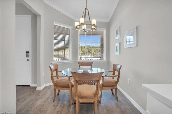Dining area with wood finish floors, baseboards, an inviting chandelier, and ornamental molding