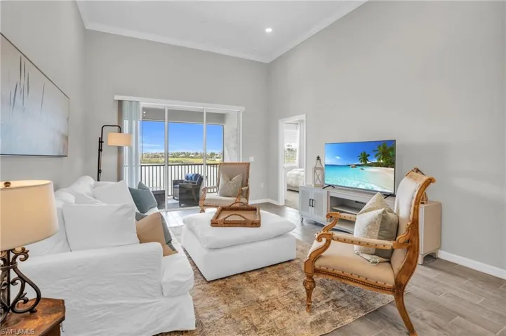 Living area with crown molding, wood finished floors, baseboards, and a towering ceiling