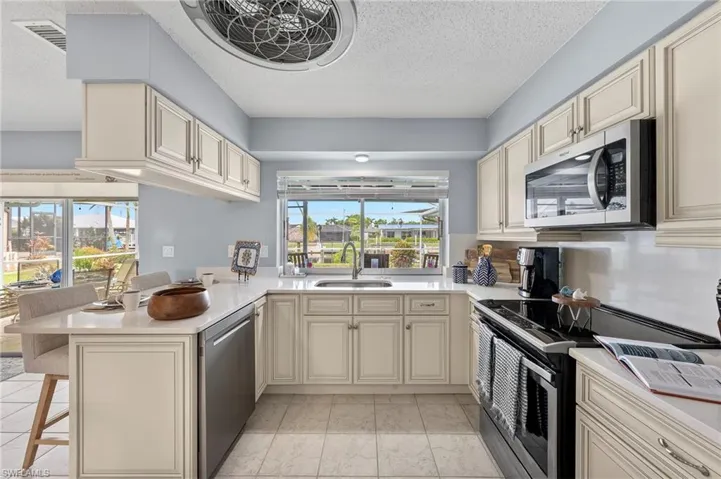Kitchen featuring sink, stainless steel appliances, cream cabinetry, and kitchen peninsula