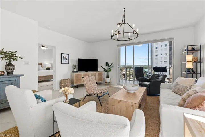 Tiled living room with ceiling fan with notable chandelier
