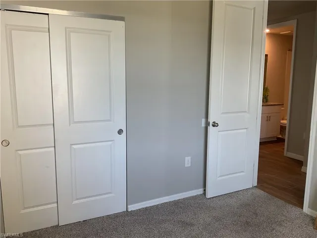 Unfurnished bedroom with a closet, baseboards, and carpet