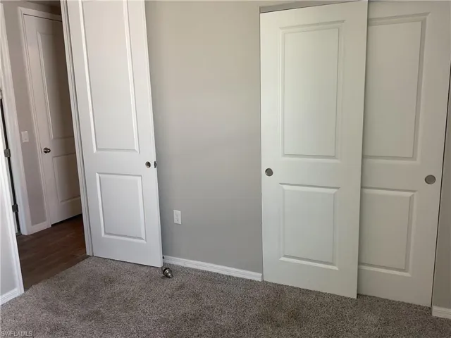 Unfurnished bedroom with baseboards and carpet floors