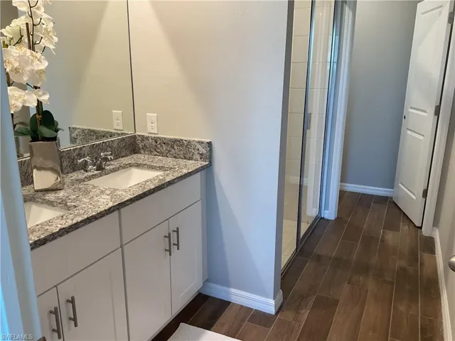 Full bathroom with wood tiled floor, double vanity, baseboards, and a sink