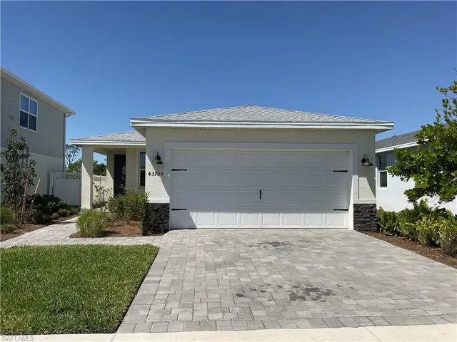 View of front of house featuring fence, stucco siding, a garage, stone siding, and decorative driveway