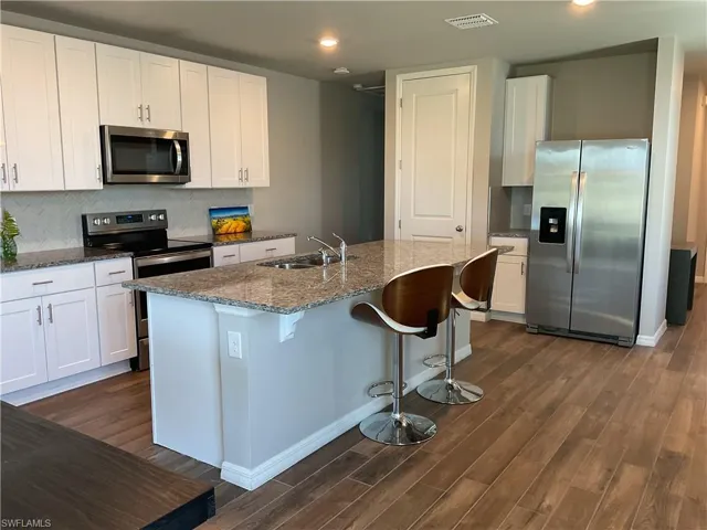 Kitchen featuring visible vents, dark wood-type flooring, a sink, appliances with stainless steel finishes, and decorative backsplash