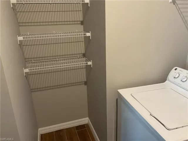 Washroom featuring baseboards, laundry area, washer / clothes dryer, and wood finish floors