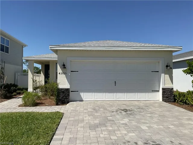 View of front of home featuring stone siding, stucco siding, driveway, and an attached garage