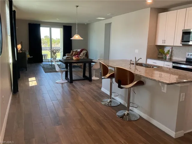 Kitchen with a sink, decorative backsplash, appliances with stainless steel finishes, and dark wood-style floors