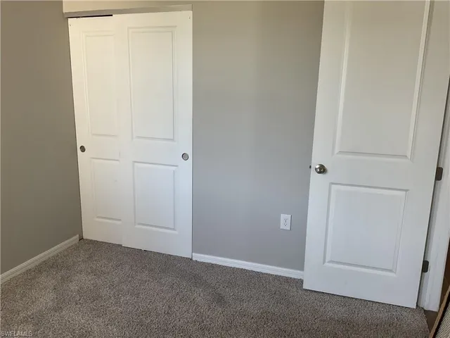 Unfurnished bedroom featuring carpet, baseboards, and a closet
