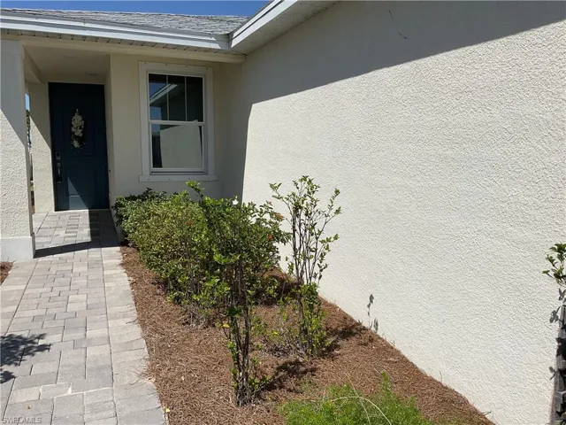 Entrance to property with stucco siding and roof with shingles