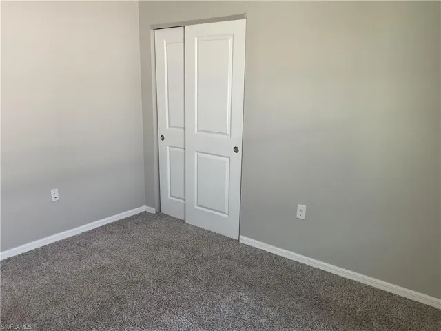 Unfurnished bedroom with a closet, baseboards, and carpet