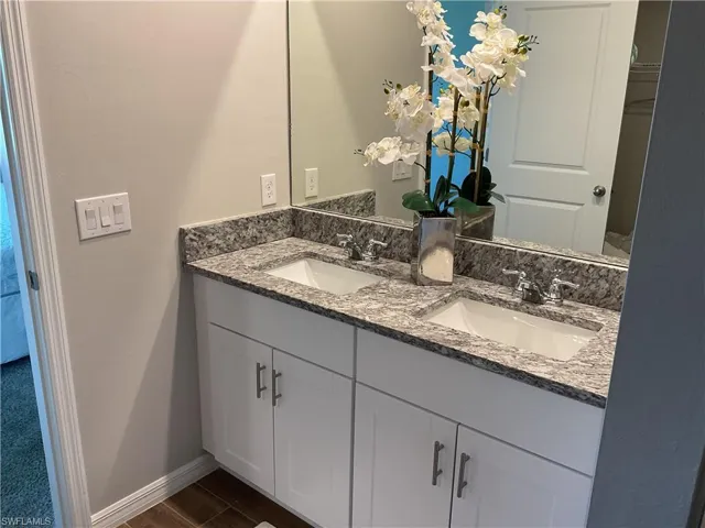 Bathroom with double vanity, wood finished floors, baseboards, and a sink