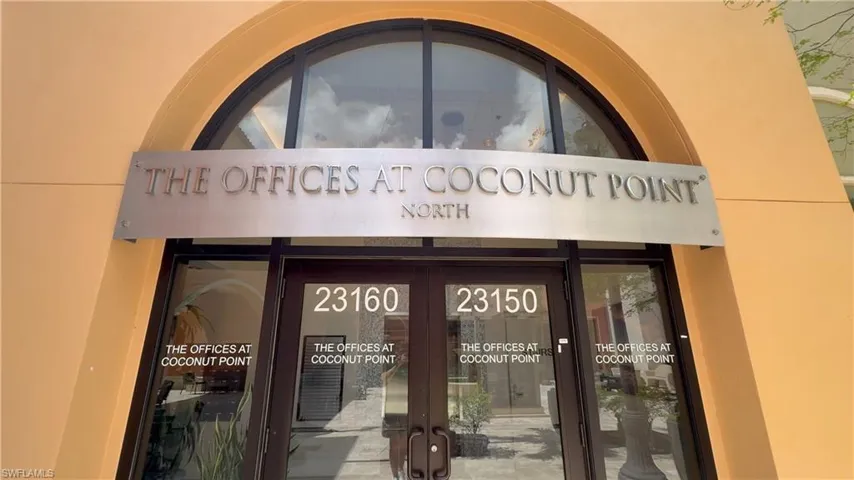 Commercial entrance featuring a prominent arched window and a brushed metal sign