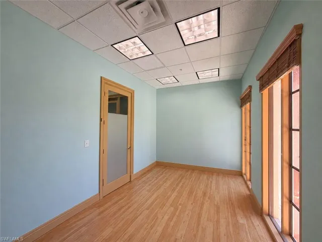 Light wood-finish flooring complements the pale blue walls in this room, featuring multiple windows with integrated blinds