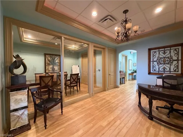 Open-concept interior featuring wood-finish flooring, a recessed ceiling with crown molding, and an arched doorway