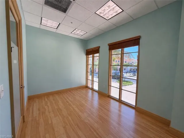 Light wood-finish flooring complements the pastel blue walls and wood-framed windows