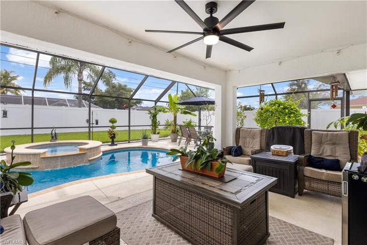 oversized lanai with multiple seating areas, pool, and spa with waterfall