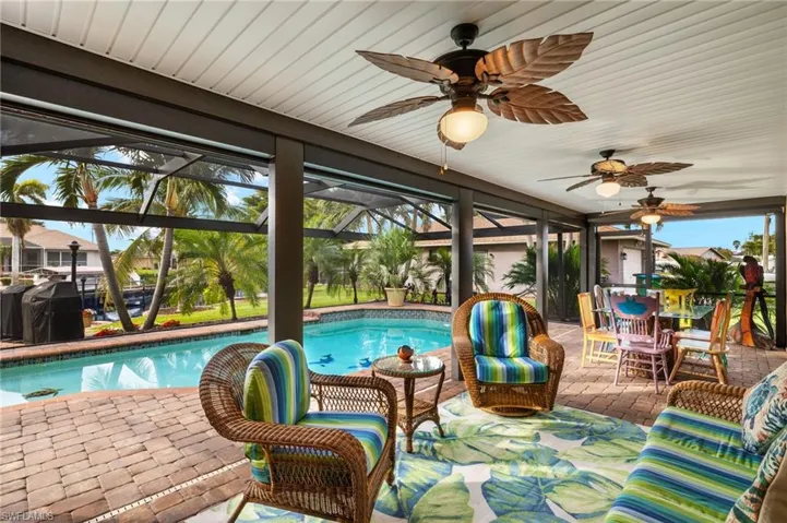 View of swimming pool featuring glass enclosure, ceiling fan, area for grilling, and a patio
