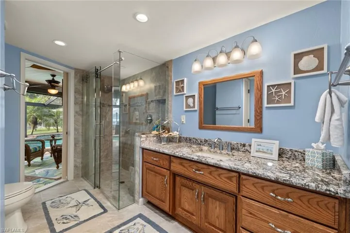 Bathroom featuring toilet, vanity, and a shower with door