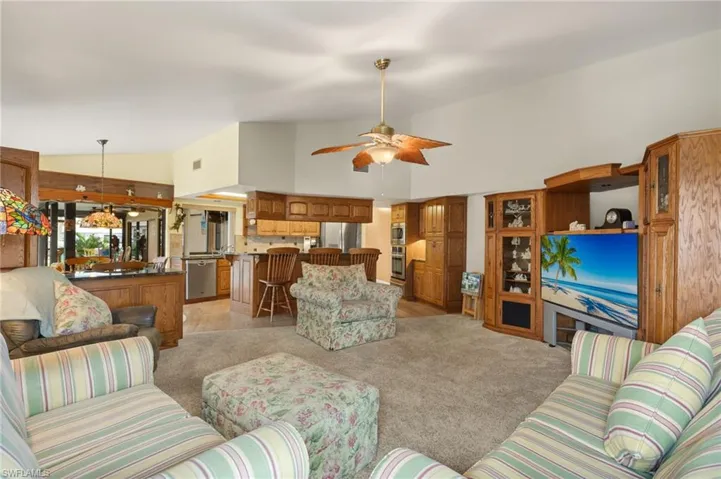 Living room featuring light carpet, ceiling fan, and high vaulted ceiling