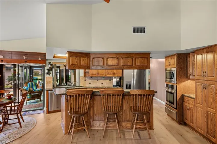 Kitchen with a breakfast bar area, stainless steel appliances, a high ceiling, and a center island