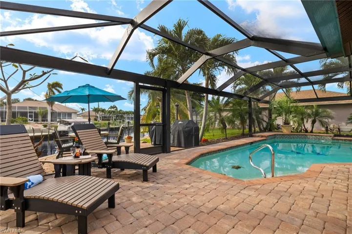 View of swimming pool featuring grilling area, glass enclosure, and a patio area
