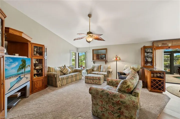 Living room featuring ceiling fan, lofted ceiling, and light carpet