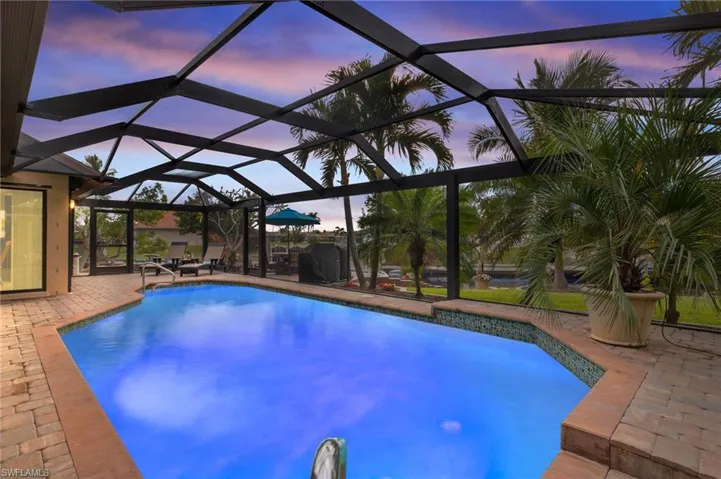 Pool at dusk featuring a patio area and a lanai