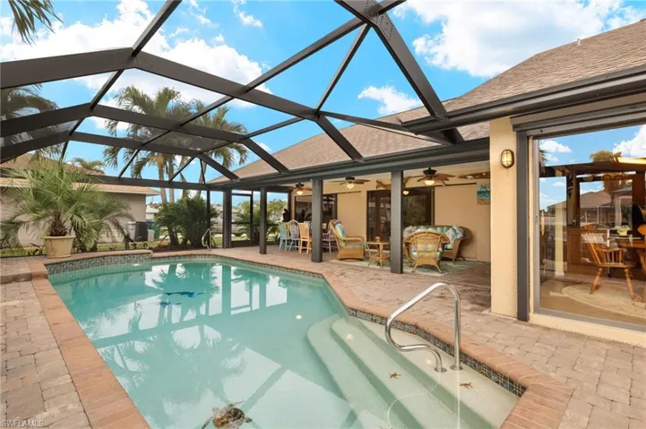 View of swimming pool with ceiling fan, glass enclosure, an outdoor living space, and a patio
