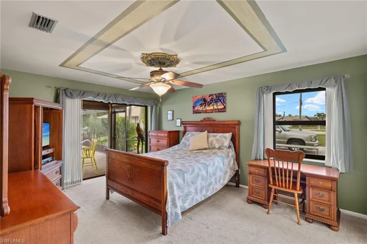 Bedroom with ceiling fan, access to exterior, and light colored carpet