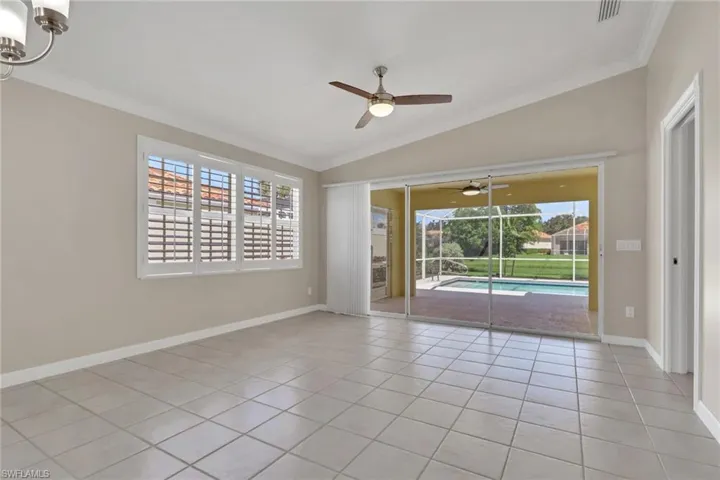 Tiled flooring throughout, vaulted ceiling, and sliding glass doors opening to a screened patio with a pool
