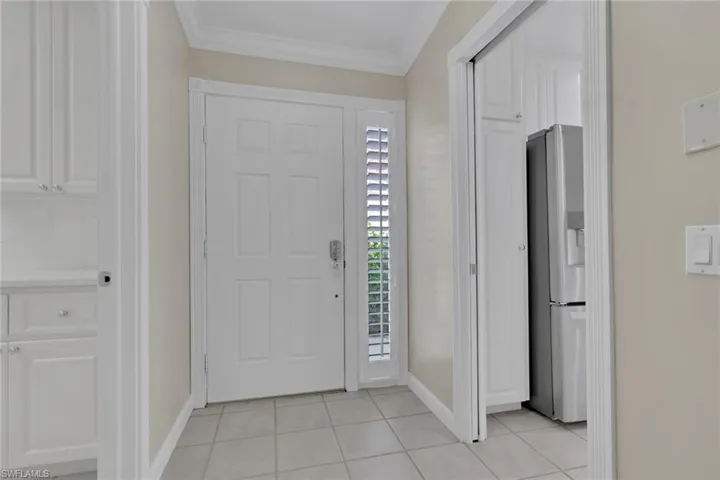Entryway with tile flooring and crown molding