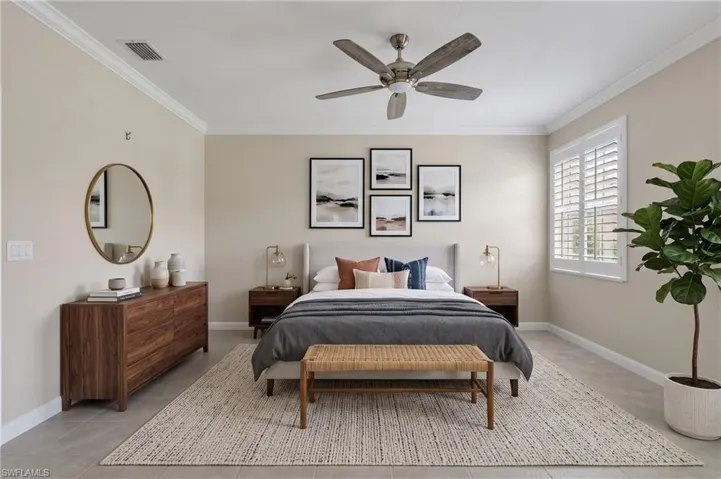 Crown molding details, ceiling fan with light fixture, window with plantation shutters, light gray flooring, and neutral wall tones