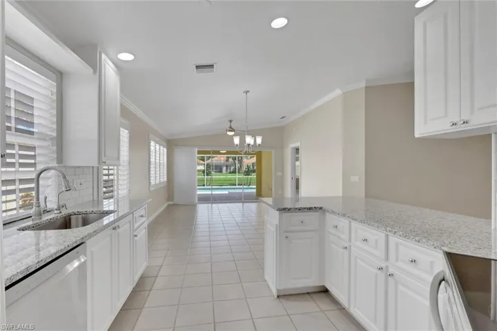 White shaker-style cabinetry with chrome hardware, speckled countertops, stainless steel sink with gooseneck faucet, white subway tile backsplash, and recessed lighting
