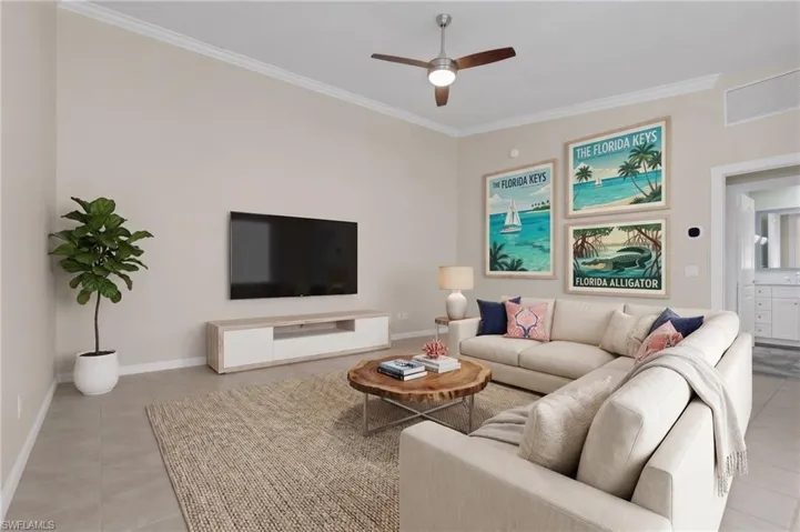 Vaulted ceiling with crown molding, ceiling fan, tile flooring, and integrated wall-mounted media console