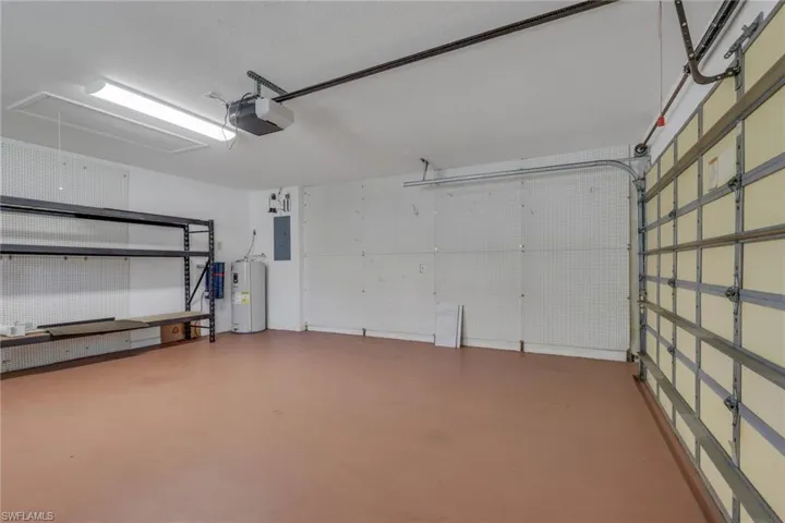 Garage space featuring a roller garage door, built-in shelving, and a water heater