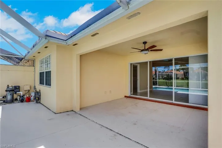 Expansive covered patio featuring a ceiling fan, sliding glass doors, and concrete flooring