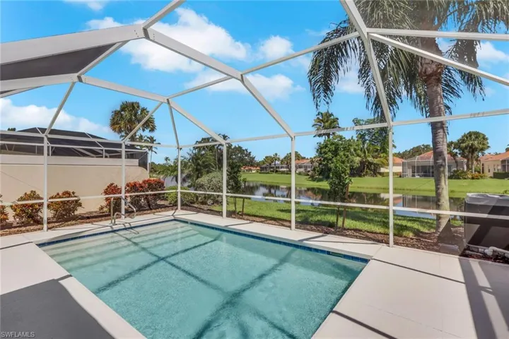 Screened pool enclosure featuring a rectangular swimming pool with integrated steps, a spacious paved deck, and tropical landscaping