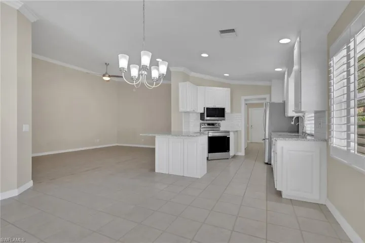 Open-concept kitchen with white cabinetry, stainless steel appliances, and a breakfast bar
